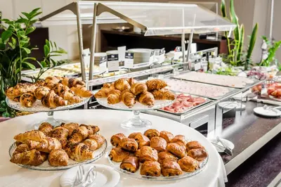 a buffet line with trays of pastries and other food at Eurostars Roma Aeterna in Rome