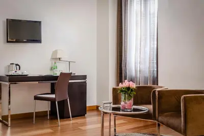 a living room with a desk and chairs and a table at Eurostars Roma Aeterna in Rome