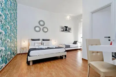 a white bedroom with a bed and a chair at Residenza Musei Vaticani in Rome