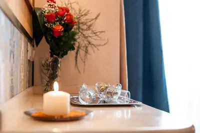 a candle and a tray of glasses and a vase with roses at Affittacamere Guest House Glatimia in Rome