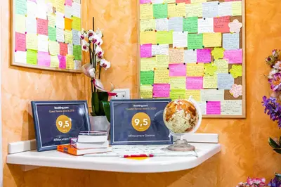two monitors on a table with a wall with papers at Affittacamere Guest House Glatimia in Rome