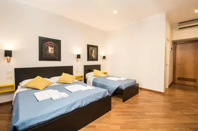 a bedroom with two beds with yellow pillows at Seven Rooms Vatican in Rome