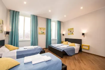 a hotel room with two beds and blue curtains at Seven Rooms Vatican in Rome