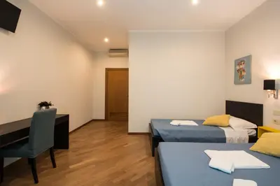 a room with two beds and a desk and a table at Seven Rooms Vatican in Rome