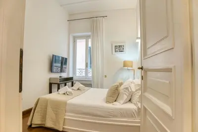 a bedroom with a bed with white sheets and a window at Orsoline Boutique Apartments - Best position in Rome in Rome