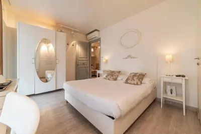 a white bedroom with a large bed and a mirror at Nina Casetta De Trastevere in Rome