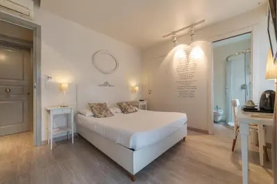 a white bedroom with a bed and a desk and a sink at Nina Casetta De Trastevere in Rome