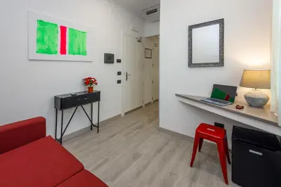 a living room with a red couch and a desk with a laptop at Crossroad Hotel in Rome