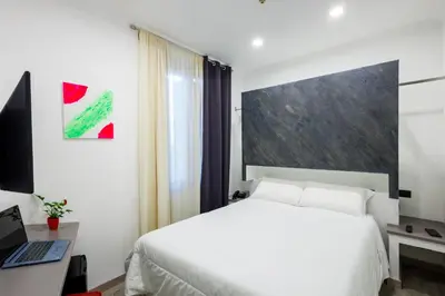 a bedroom with a bed and a desk with a laptop at Crossroad Hotel in Rome