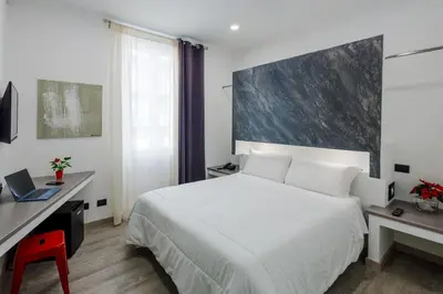 a bedroom with a white bed and a desk with a laptop at Crossroad Hotel in Rome