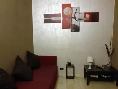 a living room with a red couch and paintings on the wall at Casa Tua a Piazza del Popolo in Rome