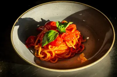 a bowl of pasta with tomatoes and basil on it at hu Roma Camping In Town in Rome