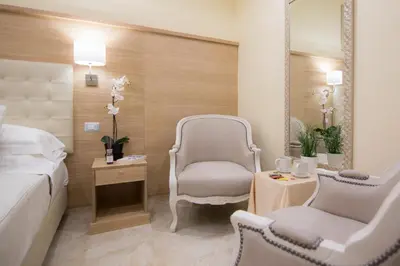 a bedroom with a bed and two chairs and a mirror at Esposizione Palace Hotel in Rome