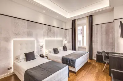 a hotel room with two beds and a desk at The Liberty Boutique Hotel in Rome