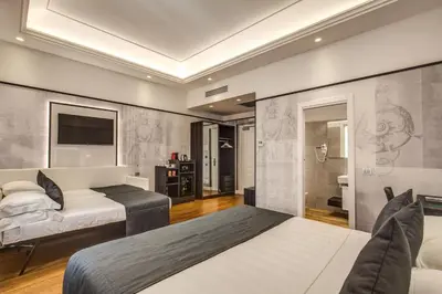 a bedroom with two beds and a tv and a bathroom at The Liberty Boutique Hotel in Rome