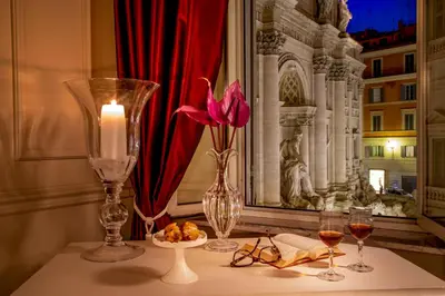 a table with a candle and glasses and a flower at Trevi Ab Aeterno - Amazing View of the Trevi Fountain in Rome
