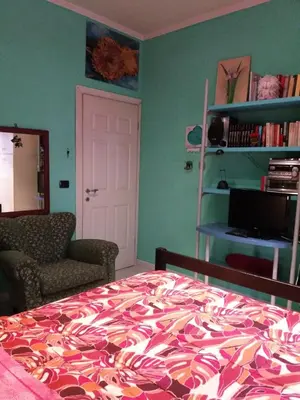 a bedroom with a bed and a chair and a book shelf at Anna Vì Guest Home in Rome