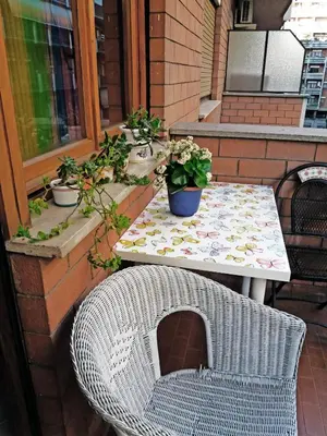 a wicker chair sitting next to a table on a patio at Anna Vì Guest Home in Rome