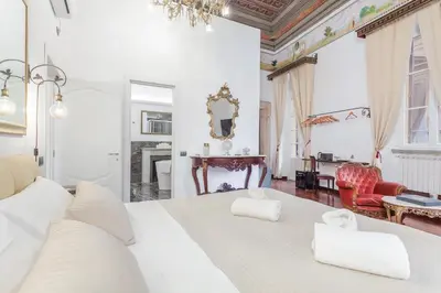 a bedroom with a large white bed and a living room at Palazzo Del Duca Piazza Navona Campo dei Fiori Piazza del Fico Guest House in Rome