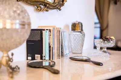 a table with books and glasses and a mirror at Palazzo Del Duca Piazza Navona Campo dei Fiori Piazza del Fico Guest House in Rome