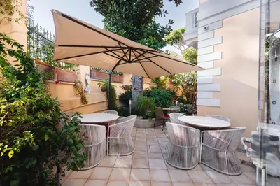 a patio with tables and chairs and an umbrella at Sourire Hotel in Rome
