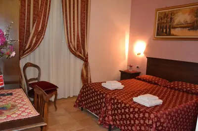 a hotel room with a bed and a vase of flowers at Bye Rome Guesthouse in Rome