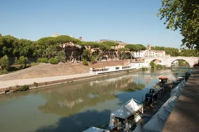 a boat is docked in a river next to a bridge at Trastevere classico self check in in Rome