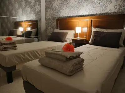 two beds in a hotel room with towels on a table at Vatican69 New Apartment in Rome