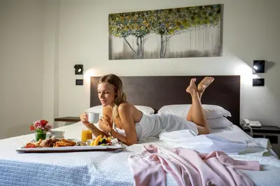 a woman laying on a bed with a plate of food at Hotel Oxford in Rome