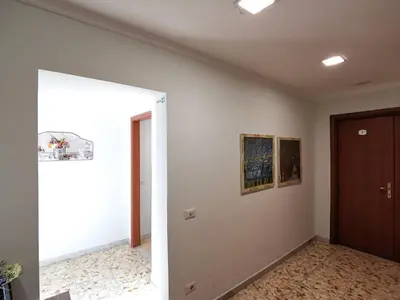 a hallway with a door and paintings on the wall at St. Anthony Guest House in Rome