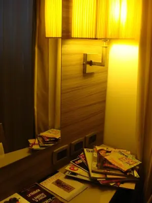a lamp on a table with a mirror and magazines at Morrisson Exclusive Rooms in Rome