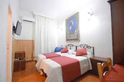 a bedroom with two beds with red and white sheets at Hotel Alexis in Rome