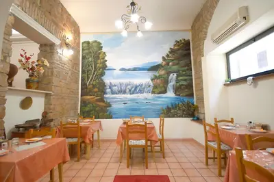 a restaurant with tables and a painting on the wall at Hotel Alexis in Rome
