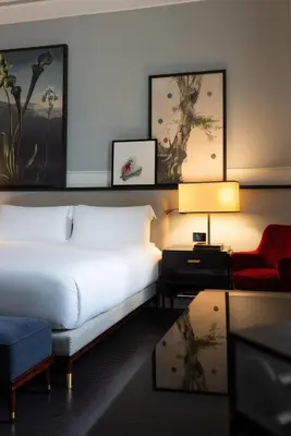 a bedroom with a white bed and a red chair at Hotel Vilòn - Small Luxury Hotels of the World in Rome