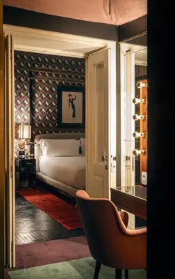 a bedroom with a bed and a chair and a window at Hotel Vilòn - Small Luxury Hotels of the World in Rome