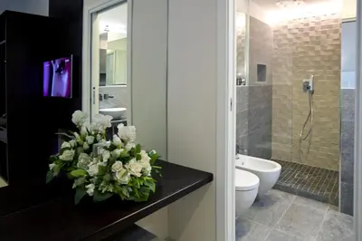 a bathroom with a toilet and a vase of flowers on a counter at Roman Holidays Boutique Hotel in Rome