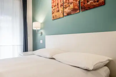 a bedroom with a bed with white sheets at Rome Vatican Rooms in Rome