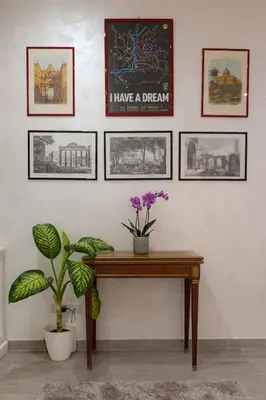 a table with plants and pictures on a wall at M&M House in Rome