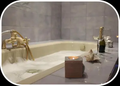 a bathroom with a bath tub with a candle and wine glasses at San Peter's Golden Rooms in Rome