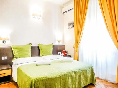 a bedroom with a bed with green sheets and a window at B&B Morelli 1 in Rome