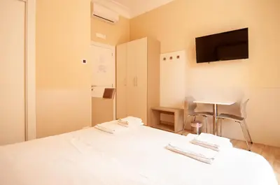 a bedroom with a white bed with a tv on the wall at Domus Porta Angelica in Rome