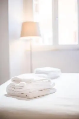 two white towels sitting on a table with a lamp at Piazza Cavour Suite in Rome