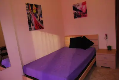 a bedroom with a bed with purple sheets and posters on the wall at Stefy's Rooms in Rome