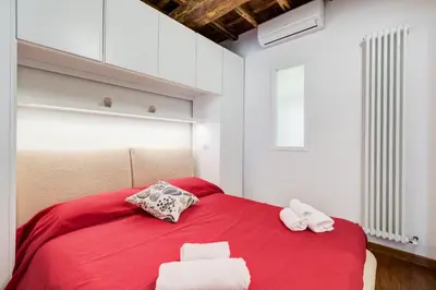 a bedroom with a red bed with two towels on it at Piazza Navona-Coronari House in Rome
