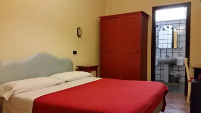 a bedroom with a bed and a red cabinet at Hotel Croce Di Malta in Rome