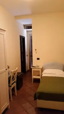 a bedroom with a bed and a table and a chair at Hotel Croce Di Malta in Rome