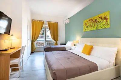 a hotel room with two beds and a desk and a television at Aurelia Home Guest House in Rome