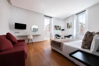 a bedroom with a bed and a couch and a tv at Mascherino Suites in Rome