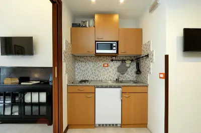 a small kitchen with wooden cabinets and a microwave at 4BNB - Cavour Square Apartment in Rome