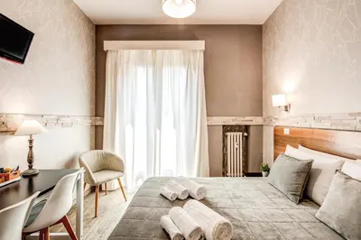 a bedroom with a bed and a desk and a window at Santamaria Inn in Rome